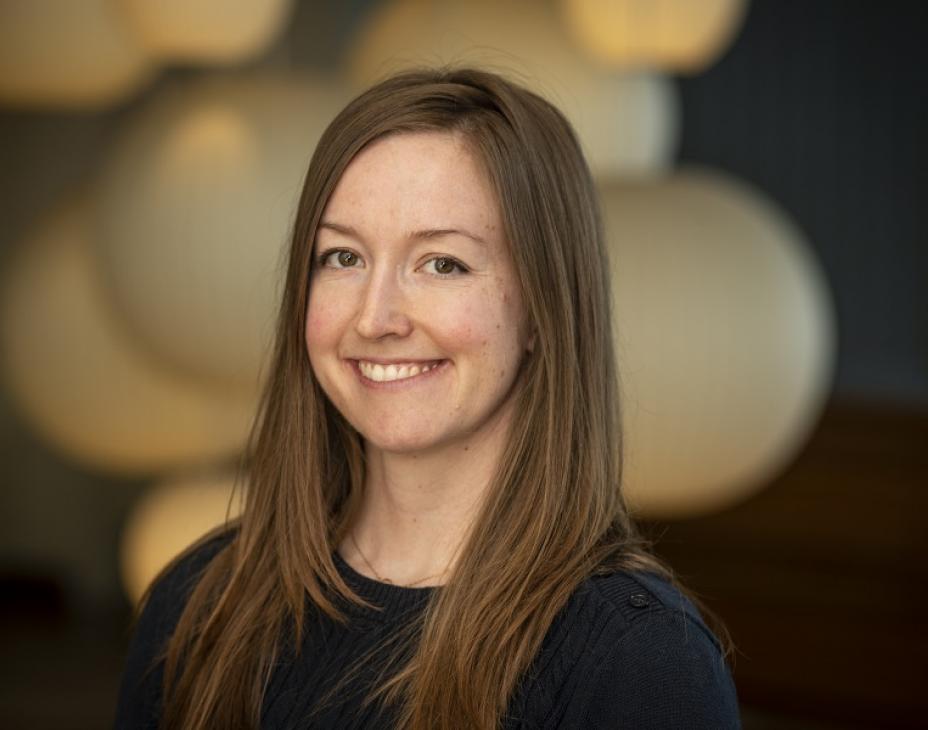 Dr. Molly Taylor smiling facing forward. She has shoulder-length brown hair and is wearing a black shirt.