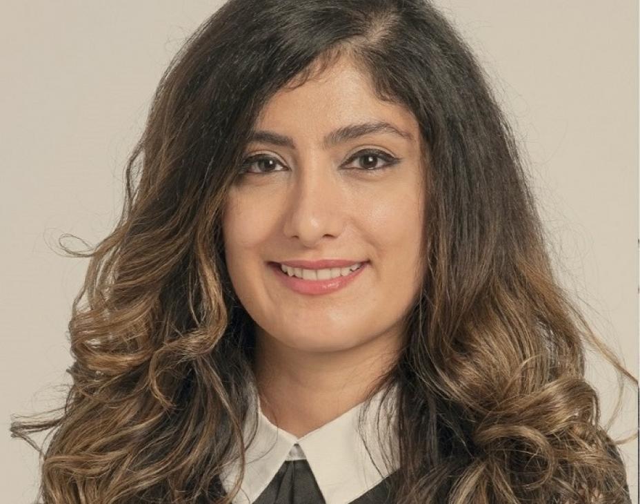 Dr. Bahar Laderian, wearing a black blouse with a white collar. She has arm-length wavy brown hair and is smiling facing forward.