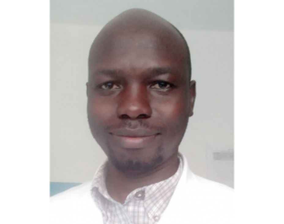 Headshot of Dr. Clement Dove Okello. He is wearing a white coat and is smiling facing forward.