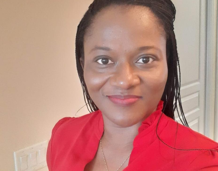 Dr. Aba Scott wearing a red shirt and smiling facing forward. She has shoulder-length black hair.