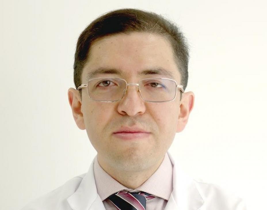 Dr. Luis L. Rojas Puentes headshot. He is facing forward against a beige background and wearing a white coat.