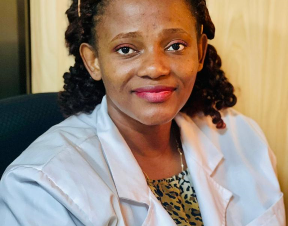 Dr. Sarah Nyagabona in a white coat and smiling facing forward in a clinical setting.