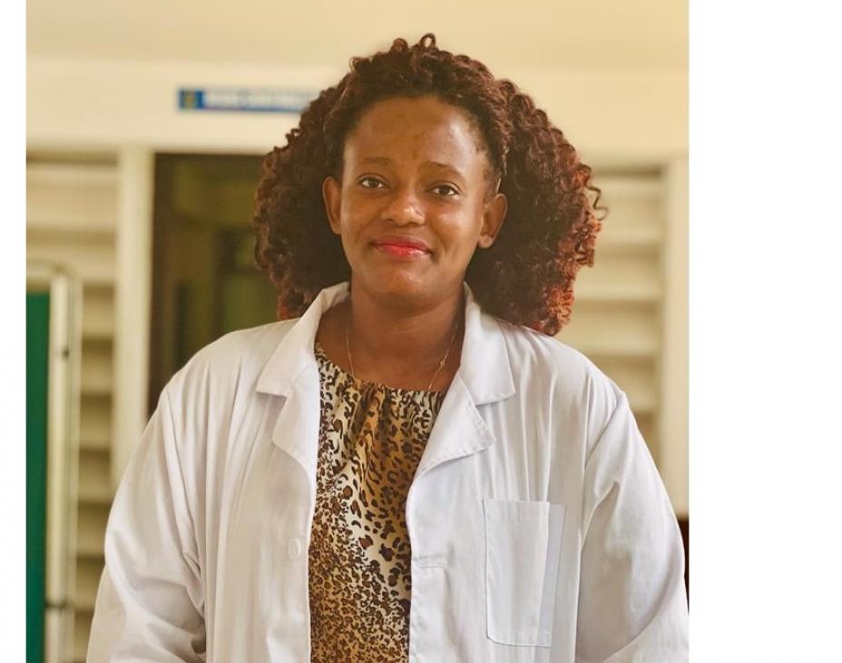 Dr. Sarah Nyagabona in a white coat and smiling facing forward in a clinical setting.