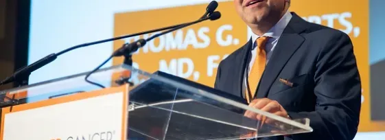 Dr. Thomas Roberts speaking at a podium at the 2019 ASCO Annual Meeting.