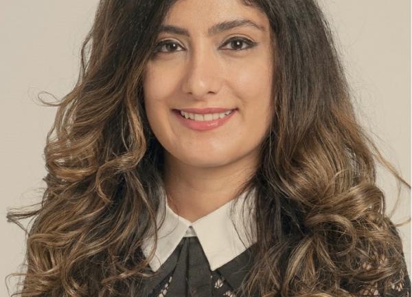 Dr. Bahar Laderian, wearing a black blouse with a white collar. She has arm-length wavy brown hair and is smiling facing forward.