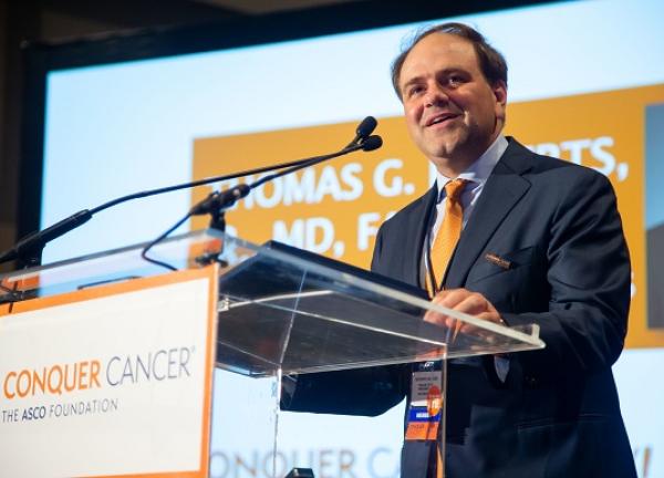Dr. Thomas Roberts speaking at a podium at the 2019 ASCO Annual Meeting.