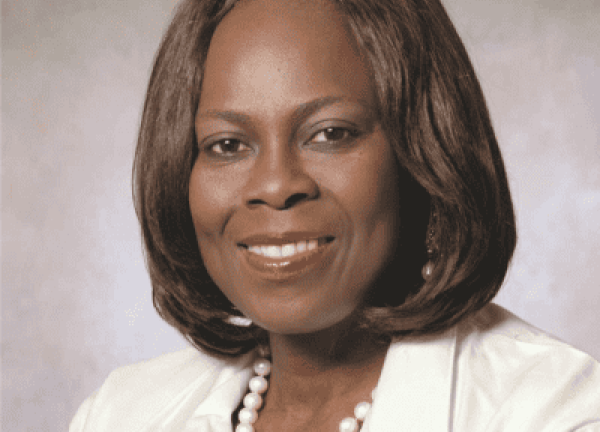 Dr. Olopade headshot. She is smiling, facing forward, wearing a white jacket, with a white pearl necklace.