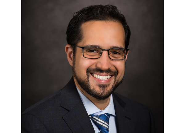 Dr. Pavlos Msaouel headshot; he is smiling facing forward against a dark-gray background.