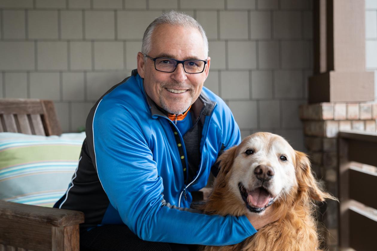 Mark Crafts pictured smiling with his golden retriever dog on his front porch