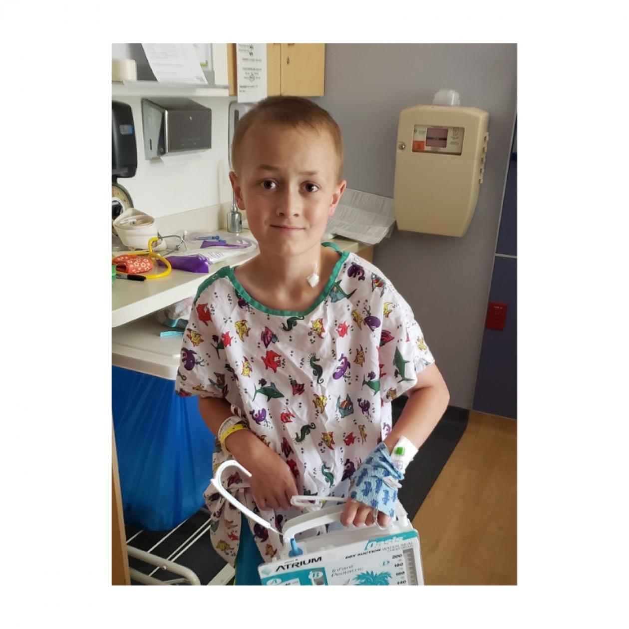 Cain, a 12-year-old patient with Ewing sarcoma, wearing a hospital gown and facing forward