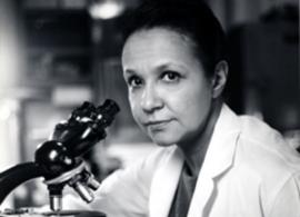 Dr. Jane C. Wright in a lab coat using a microscope to conduct clinical research