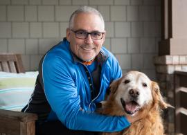 Mark Crafts pictured smiling with his golden retriever dog on his front porch