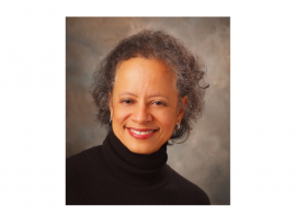 Dr. Lori Pierce wearing a black neck-collar sweater. She is smiling facing forward.