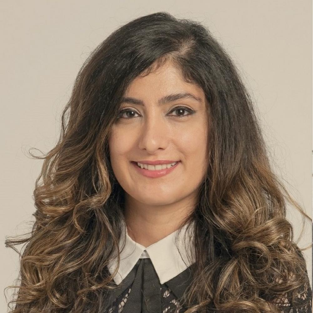 Dr. Bahar Laderian, wearing a black blouse with a white collar. She has arm-length wavy brown hair and is smiling facing forward.