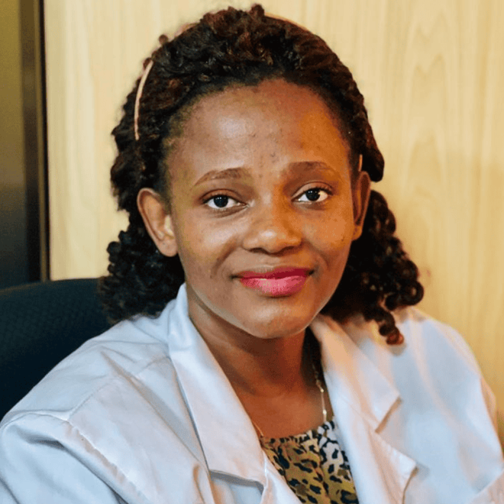 Dr. Sarah Nyagabona in a white coat and smiling facing forward in a clinical setting.