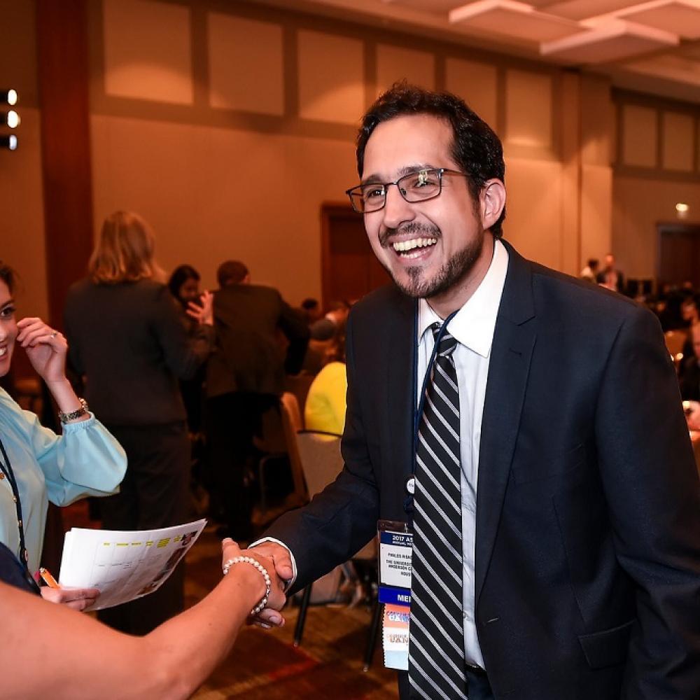 Dr. Pavlos Msaouel at the 2017 ASCO Annual Meeting. He's laughing and shaking hands with someone after receiving his Conquer Cancer grant.