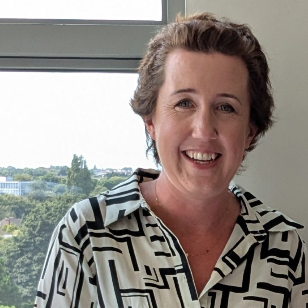 Aisling O'Brien smiling facing forward near a window