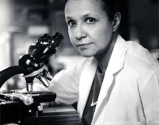 Dr. Jane C. Wright in a lab coat using a microscope to conduct clinical research