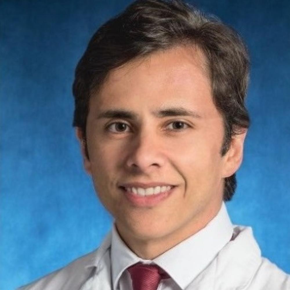 Dr. Pedro Isaacsson Velho in a white coat, smiling facing forward against a blue background.